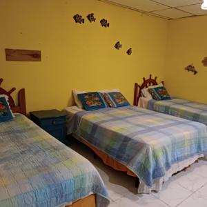 two beds in a room with yellow walls at Villa Bella in Portobelo