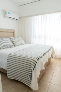 a bedroom with a bed with a striped blanket on it at Departamento Laura con Cochera in Villa María