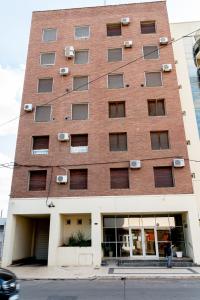 a tall brick building with a person standing in front of it at Departamento Laura con Cochera in Villa María