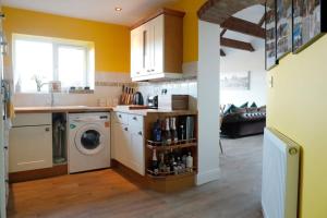 a kitchen with a washing machine and a washer at Luxury, Modern Barn Conversion in Thursford
