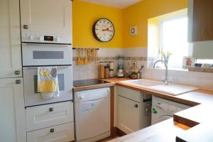 a kitchen with a sink and a clock on the wall at Luxury, Modern Barn Conversion in Thursford +5 photos