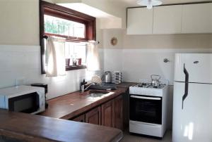 a kitchen with a white refrigerator and a sink at Cabaña La pionera in San Carlos de Bariloche