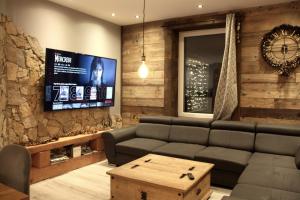 ein Wohnzimmer mit einem Sofa und einem TV in der Unterkunft Le joli bois 12 personnes 5/ch spa/sauna Gérardmer in Gérardmer