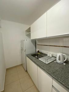 a kitchen with white cabinets and a sink and a refrigerator at Departamento Arbo y Blanco in Resistencia