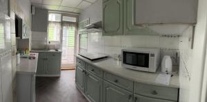 una cocina con armarios verdes y microondas en una encimera en Amazing and Romantic O2 Arena 4 Bedrooms House free parking en Londres