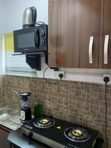 a kitchen with a stove top with a microwave at GS HOMES in Lagos