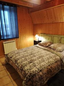 1 dormitorio con 1 cama en una habitación con paredes de madera en Chez Philopin, en Saint-Pierre-Colamine