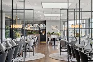 a restaurant with white tables and chairs and windows at Best Western Plus Hotel Fredericia in Fredericia