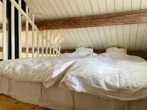 uma cama com lençóis brancos e almofadas num quarto em Backgårdens Timmerstuga em Falköping