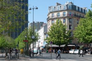 a busy city street with people walking and a building at Hôtel Odessa Montparnasse in Paris