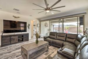 a living room with a leather couch and a flat screen tv at Stunning Goodyear Vacation Rental with Private Pool! in Goodyear