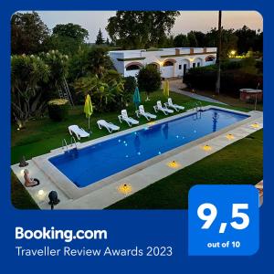 a picture of a swimming pool with chairs and a house at Devmani Hotel Rural in Espartinas