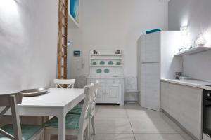 a kitchen with a white table and a white refrigerator at Merabulò in Lecce