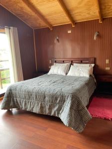 een bed in een slaapkamer met een houten muur bij Cabañas Camahueto in Chonchi