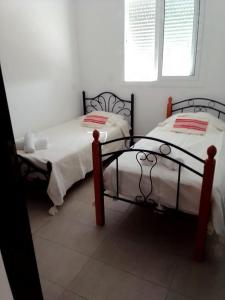 twee bedden in een kamer met witte muren bij Résidence les jardins d'assilah in Asilah