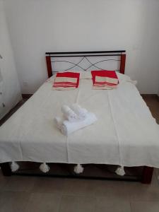 een wit bed met 2 handdoeken en rode kussens erop bij Résidence les jardins d'assilah in Asilah
