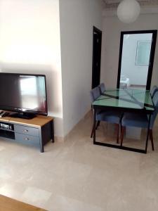 een woonkamer met een glazen tafel en een televisie bij Résidence les jardins d'assilah in Asilah