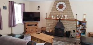 ein Wohnzimmer mit einem Kamin, einem Sofa und einem TV in der Unterkunft Hilltop Cottage/ Penrhiw in Maentwrog