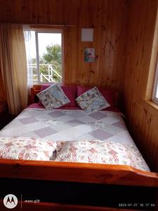 Ce lit se trouve dans une chambre en bois dotée d'une fenêtre. dans l'établissement CABAÑAS QUELLON, à Quellón