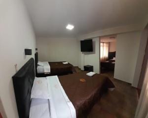um quarto de hotel com duas camas e uma televisão de ecrã plano em RONALD HOTEL em Churín