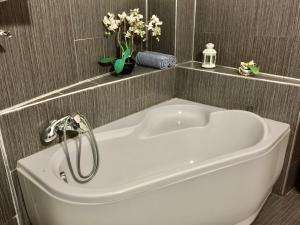 a white bath tub in a bathroom with flowers at Secession Luxury Apartment in Budapest