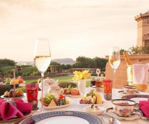 a table with plates of food and glasses of wine at Umaid Bhawan Palace Jodhpur in Jodhpur