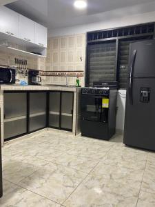 een keuken met een zwarte koelkast en een fornuis bij ALOJAMIENTO CON PARQUEO CERCA A LA BASÍLICA in Buga +11 foto's