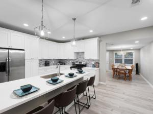 una cucina con armadi bianchi e un'isola cucina con sedie di Galveston Escapes - Walk to Beach and Restaurants a Galveston