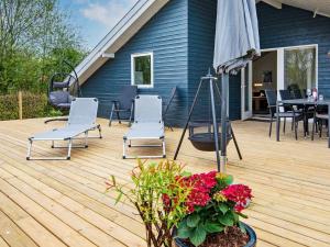 eine Terrasse mit Stühlen, einem Tisch und einem Sonnenschirm in der Unterkunft Holiday home Sydals LXXVII in Sønderby