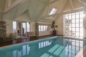 a large swimming pool in a room with windows at Hillbrook Estate Whangamata in Opoutere