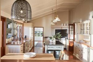 a large kitchen with white cabinets and a table at Hillbrook Estate Whangamata in Opoutere