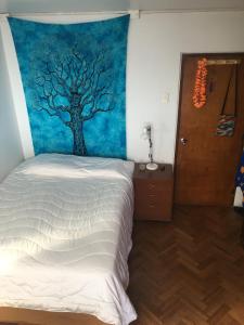 a bedroom with a bed with a tree mural on the wall at Casa Hostal Vista al Mar in Valparaíso