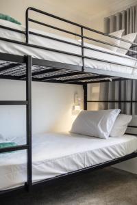 um quarto com 2 beliches e lençóis brancos em Abode Mooloolaba, Backpackers & Motel rooms em Mooloolaba