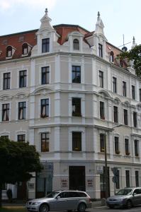 un edificio blanco con coches estacionados frente a él en Gästehaus Lisakowski Pension am Brautwiesenpark, en Görlitz