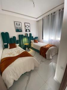 a bedroom with two beds with green chairs at Neuf et raffiné, centre ville Rabat in Rabat