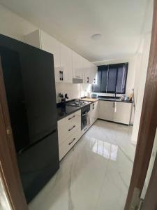 a kitchen with a black refrigerator and white cabinets at Neuf et raffiné, centre ville Rabat in Rabat