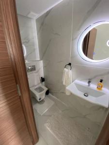 La salle de bains blanche est pourvue d'un lavabo et d'un miroir. dans l'établissement Neuf et raffiné, centre ville Rabat, à Rabat