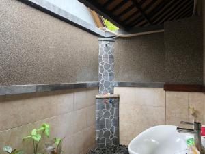 ein Bad mit einem Waschbecken und einer Dusche in der Unterkunft Pondok Shindu Guest House in Pemuteran