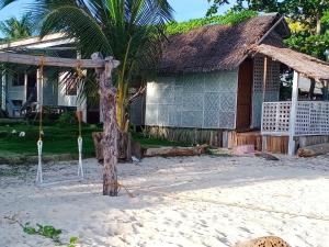 a house with a palm tree in front of it at Nitasnipahut Pamilacan island in Pamilacan