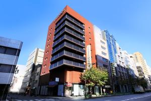 ein hohes Gebäude in einer Stadtstraße mit Gebäuden in der Unterkunft Hotel Nihonbashi Saibo in Tokio