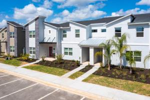 a white house with palm trees in a parking lot at Gorgeous 4Bd Close to Disney w/ Pool @ Champions Gate Resort 1196 in Davenport