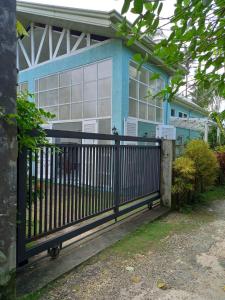 a black fence in front of a blue house at TeSario Retreat in General Luna