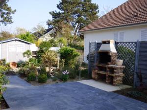 un jardín con una parrilla de ladrillo frente a una casa en Maison Jullouville, 4 pièces, 6 personnes - FR-1-361-149, en Jullouville-les-Pins