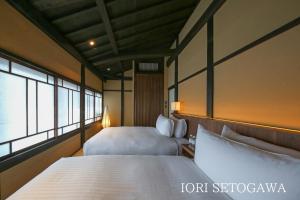 a hotel room with two beds and two windows at IORI Stay HIDA in Hida