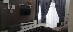 sala de estar con sofá, TV y cortinas en Sarrah Homestay At Kasa Height Residence en Kampong Alor Gajah