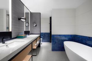un bagno con due lavandini, una vasca e piastrelle blu di Four Points by Sheraton Shenzhen Bao'an a Shenzhen