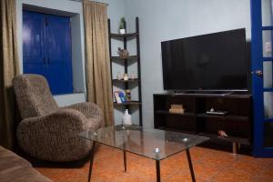 a living room with a tv and a chair and a table at Linda casa azul ubicada en el corazón de Pátzcuaro in Pátzcuaro