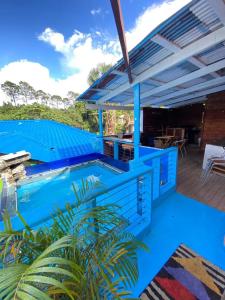 a blue swimming pool with a deck with chairs and tables at Primavera en Jarabacoa-contacto con la naturaleza in Jarabacoa