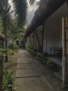 a path leading to a house with a thatched roof at mimi kuta homestay in Kuta Lombok