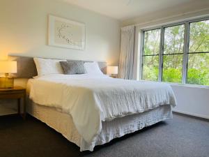 a bedroom with a white bed and a window at Cosy Apartment at Sebel Twin Waters Resort w Private Garden - 2 Mins Walk to Beach & River in Mudjimba